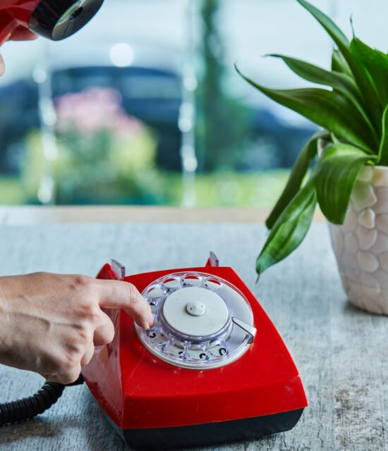Hand dialing the number on telephone in the marble background. High quality photo